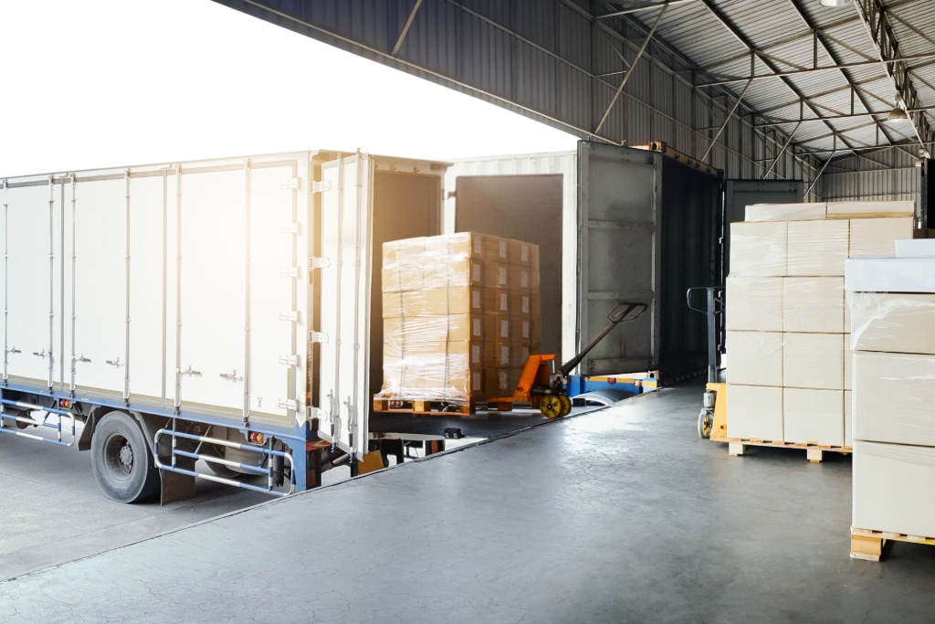 Bulk pallets of packaging boxes being loaded onto a container truck. distribution warehouse Container transport, supply chain, parcel delivery. Freight truck, logistics, transportation.