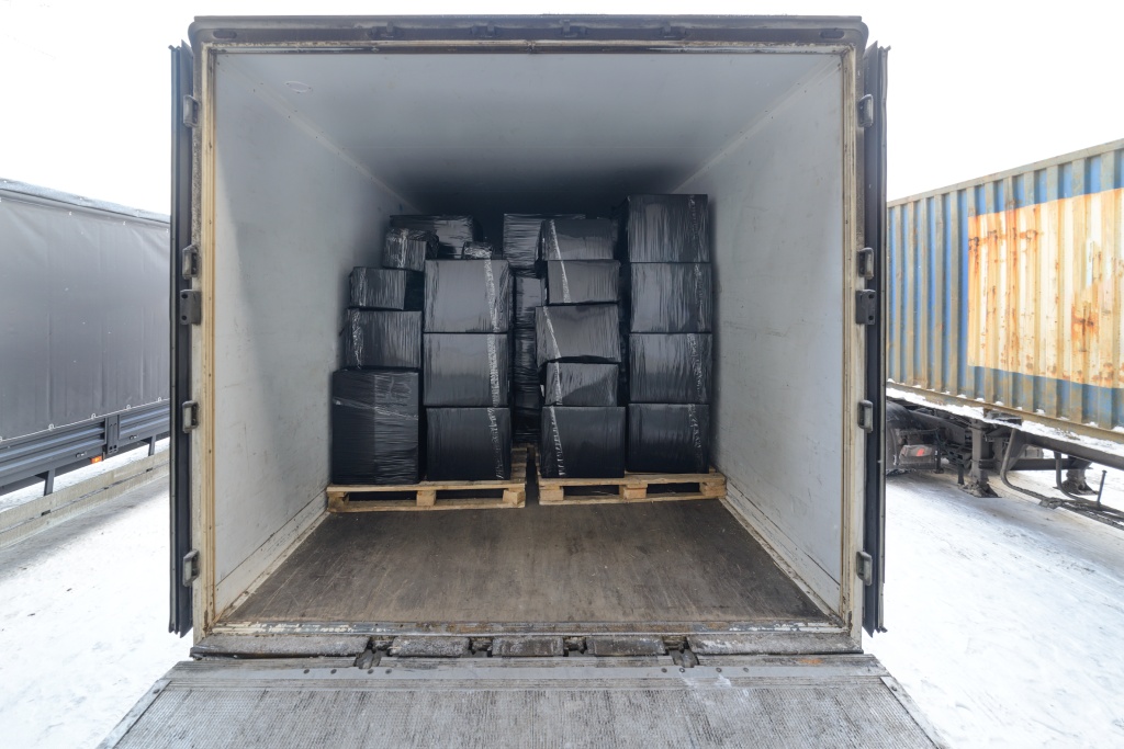 Road freight trailer loaded with boxes. Boxes wrapped in a black stretch film. Interior view of empty semi truck lorry